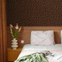 Braune Vliestapete mit Leopardenmuster an einer Schlafzimmerwand. Dekorative Tapete für ein stilvolles Ambiente.