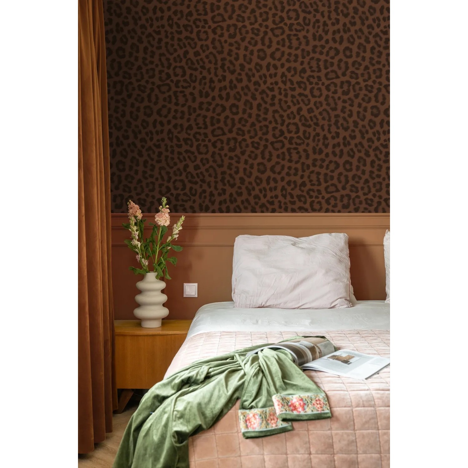 Braune Vliestapete mit Leopardenmuster an einer Schlafzimmerwand. Dekorative Tapete für ein stilvolles Ambiente.