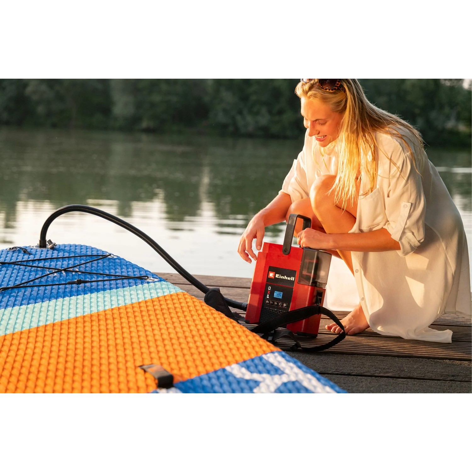 Frau pumpt SUP mit Einhell Akku-Kompressor Suppero 18/380 auf.