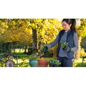 Frau benutzt Bosch Blumenkelle zum Einpflanzen im Garten.