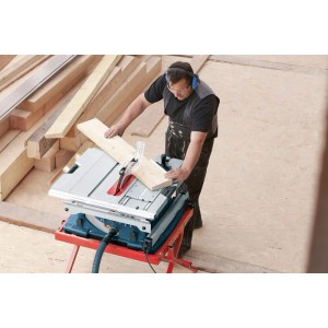 Mann sägt Holz mit Bosch Professional Tischkreissäge GTS 10 XC. Blaue Säge mit rotem Gestell, Sägeblatt Ø 254 mm.