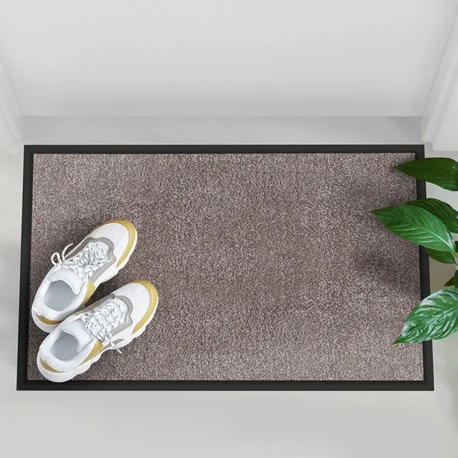 Hellbeige Karat Schmutzfangmatte Rhine (200x300 cm) mit schwarzen Rand und Schuhen.