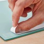 Anwendung: Hand zieht Schutzfolie von doppelseitigem fischer Montageband auf Glas.