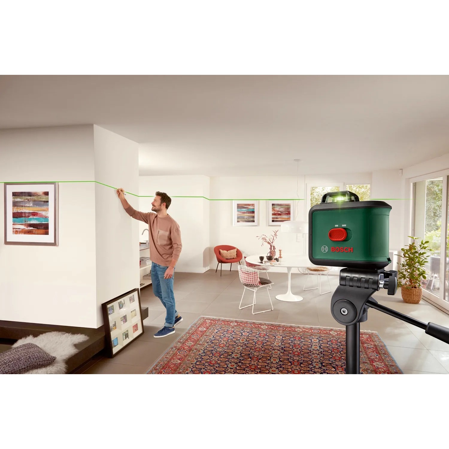 Bosch UniversalLevel 360 Kreuzlinienlaser im Einsatz mit Stativ. Grüne Laserlinie an der Wand.