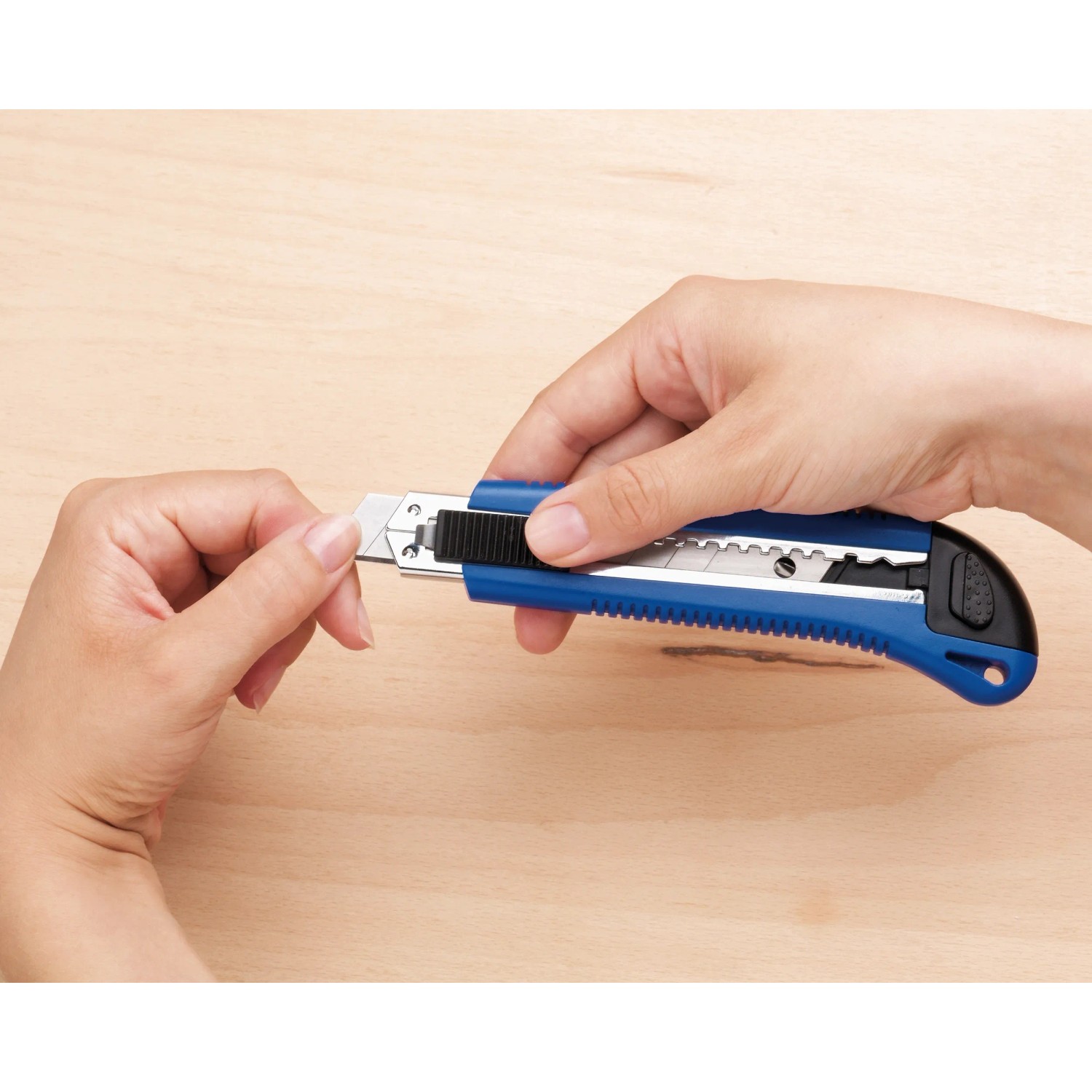 LUX Cuttermesser Classic 100 mm in Aktion: Hand schiebt Klinge heraus.