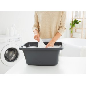 Anthrazitfarbene Rotho Wäschewanne Flowers 25 l mit Wäsche befüllt.