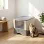 Geschlossene Katzentoilette aus weiß-grauem Kunststoff mit transparenter Tür und oberer Gitteröffnung. Eine Katze sitzt daneben.