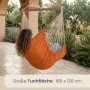 Person entspannt im großen orangefarbenen AMANKA Hängesessel (185x130 cm) aus Baumwolle auf einer Terrasse. Für Garten & Balkon.