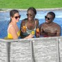 Bestway Stahlrahmenpool: Ovaler Pool mit Steinwand-Optik und drei Personen mit Getränken im Wasser.