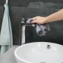 Hand reinigt Chrom-Wasserhahn mit grauem Mikrofasertuch über weißem Waschbecken. Saugstarke Putztücher für Bad.