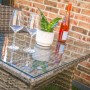 Detailansicht des Acamp Lounge-Sets Nina: Tisch mit Glasplatte, Gläser, Pflanze und Getränk. Balkonmöbel.