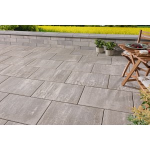 Verlegte Kann Platte Catania graualpin-nuanciert (60x40x5 cm) auf Terrasse mit Tisch und Pflanzen.