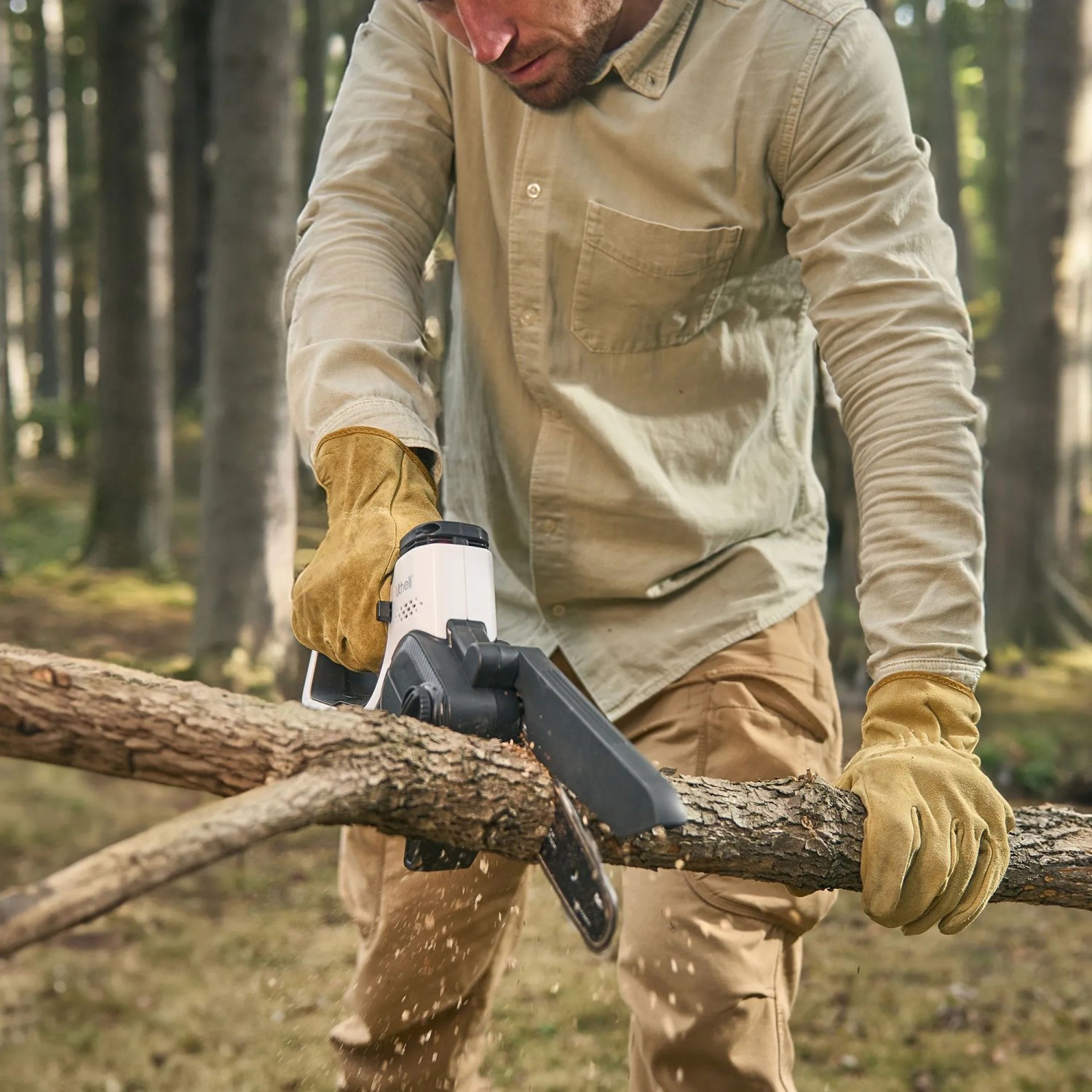 Mann sägt Ast mit Litheli Akku-Säge U20. Kompakte Akku-Kettensäge für Gartenarbeiten.