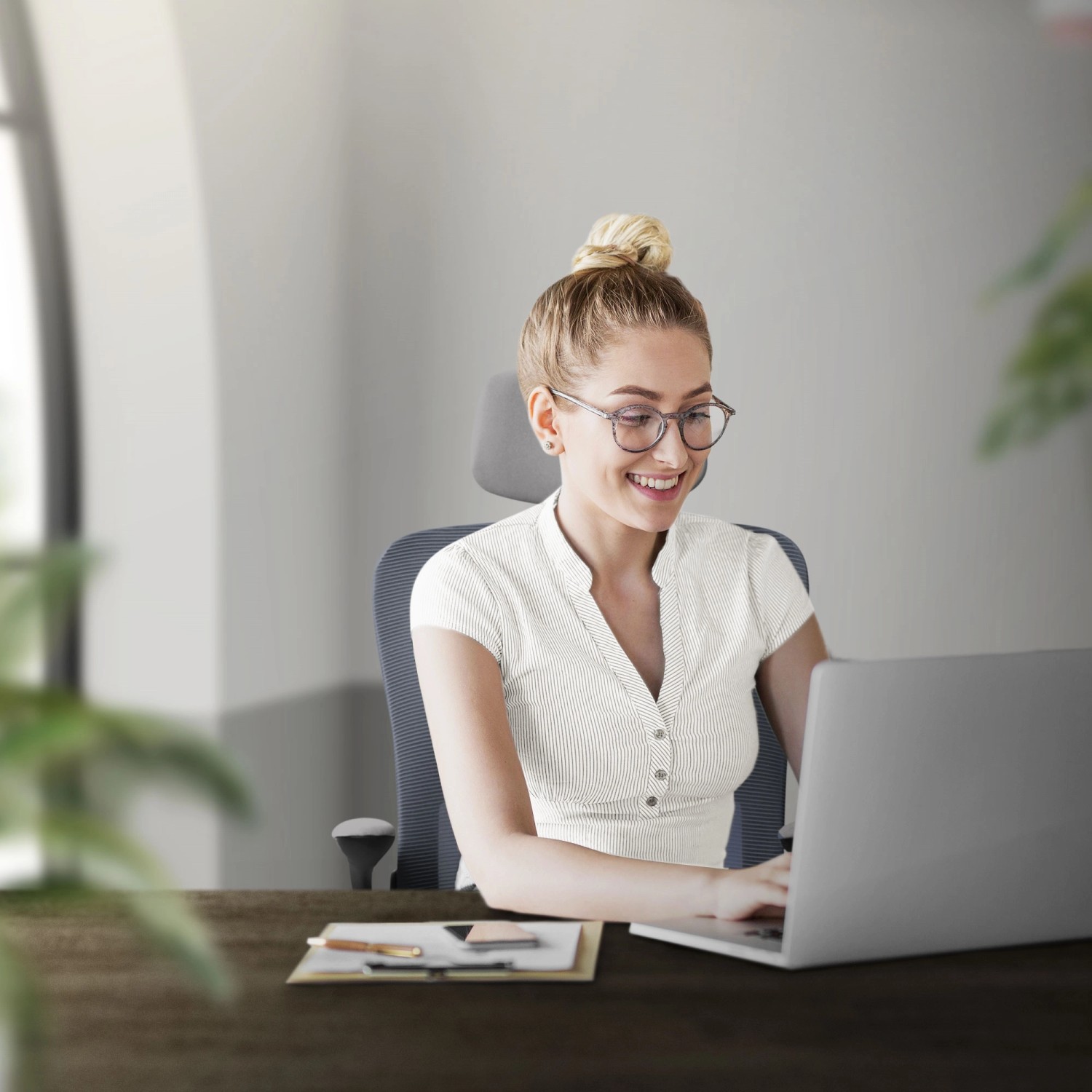 Frau sitzt auf grauem ML-Design Bürostuhl aus Mesh vor Laptop.