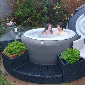 Canadian Spa Stufe in Braun für runden Whirlpool, mit Paar im Pool und Randmöbeln.
