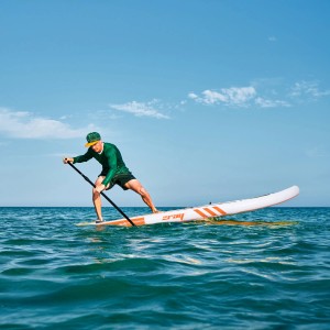 Mann auf orangefarbenem ZRAY Stand Up Paddle Board (SUP) im Wasser. Wassersport.