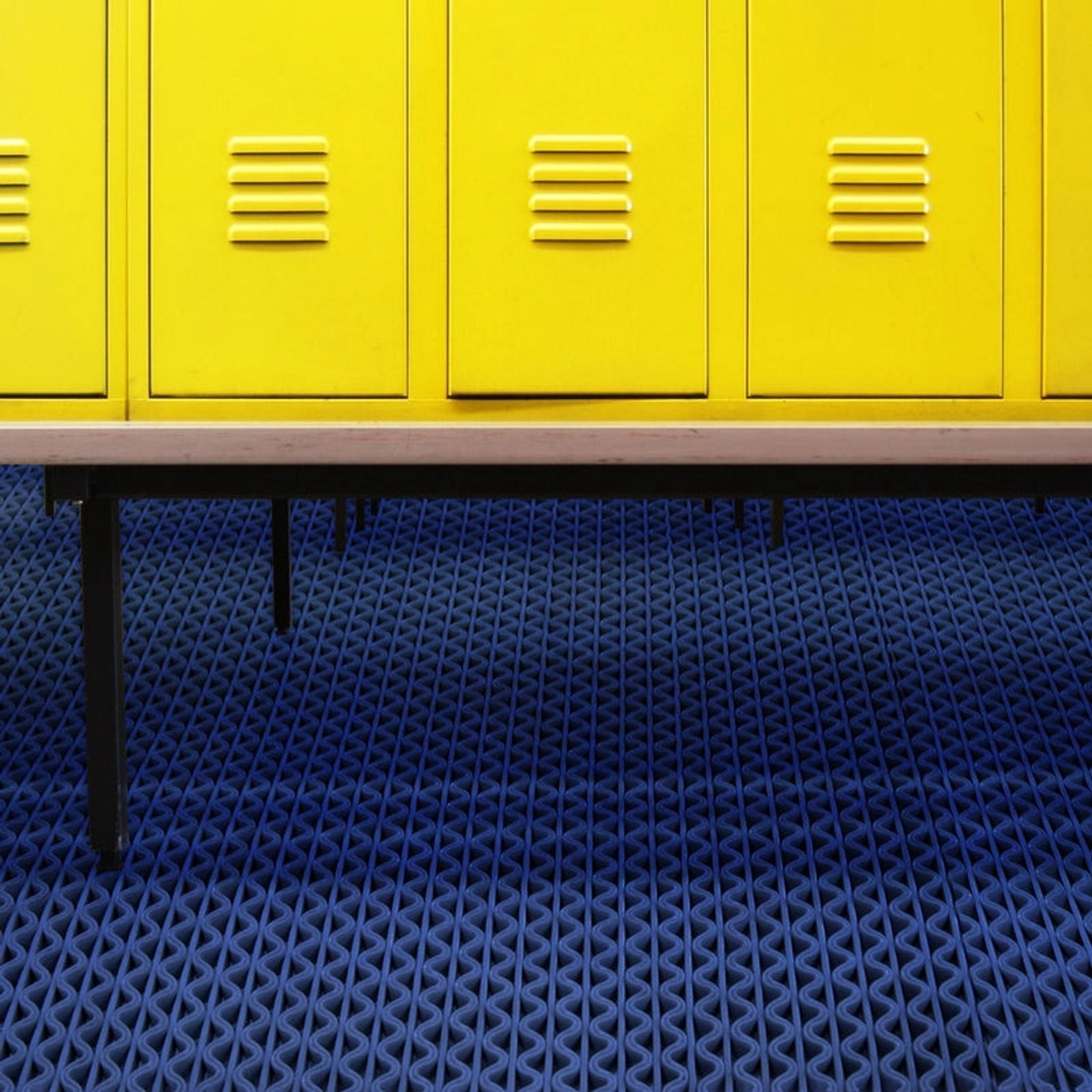 Blaue KARAT Hygienematte 120x450 cm für Barfußzonen vor gelben Spinden.