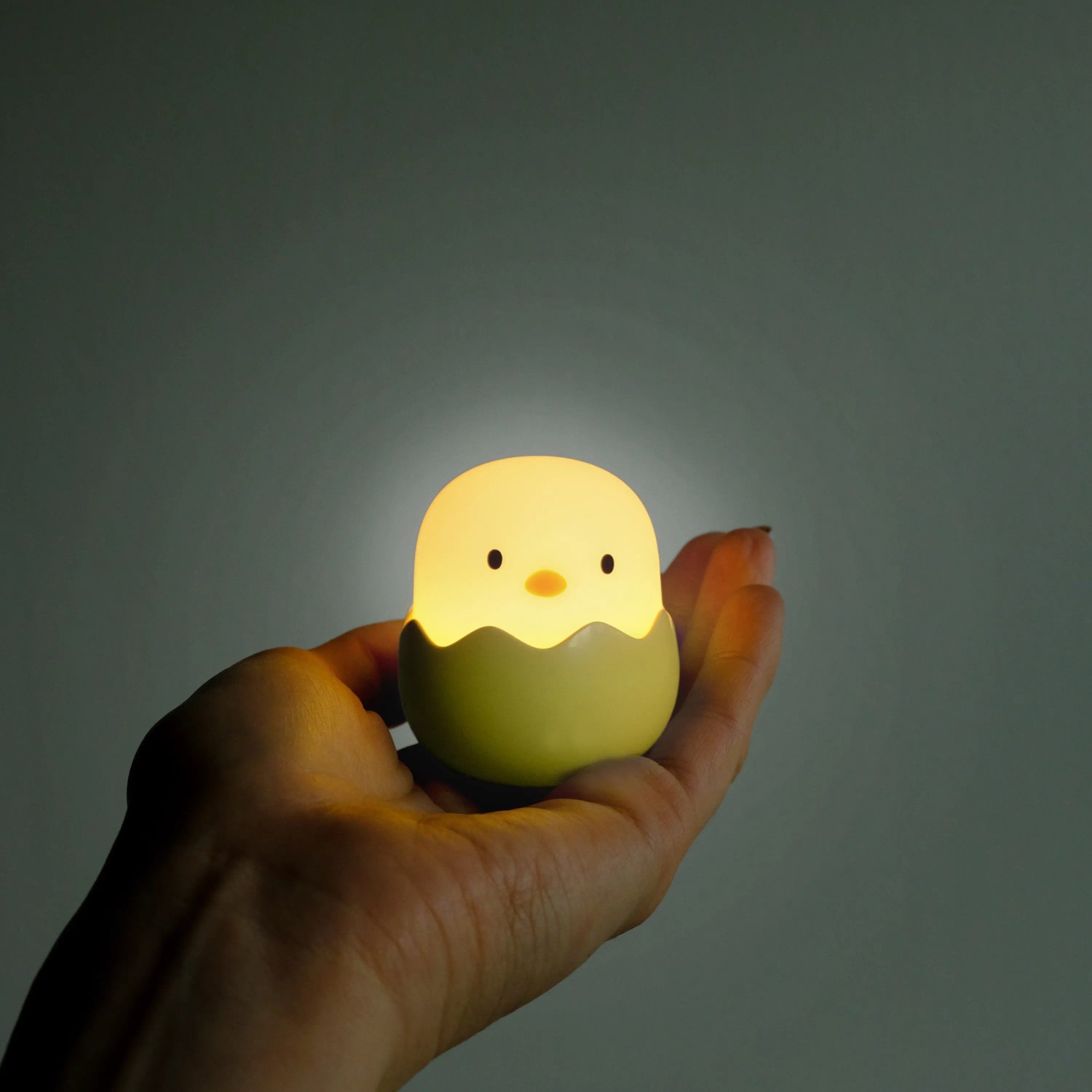 Dimmbares LED Nachtlicht Baby Eggy im 3er-Set in Hand, Kükenform.