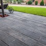 Diephaus Terrassenplatten Ruda Quarzit in Holzoptik, grau, verlegt auf einer Terrasse mit Rasenfläche.