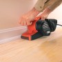 Black+Decker Bandschleifer KA86 beim Schleifen einer Sockelleiste. Die Schleifmaschine ist orange-schwarz.