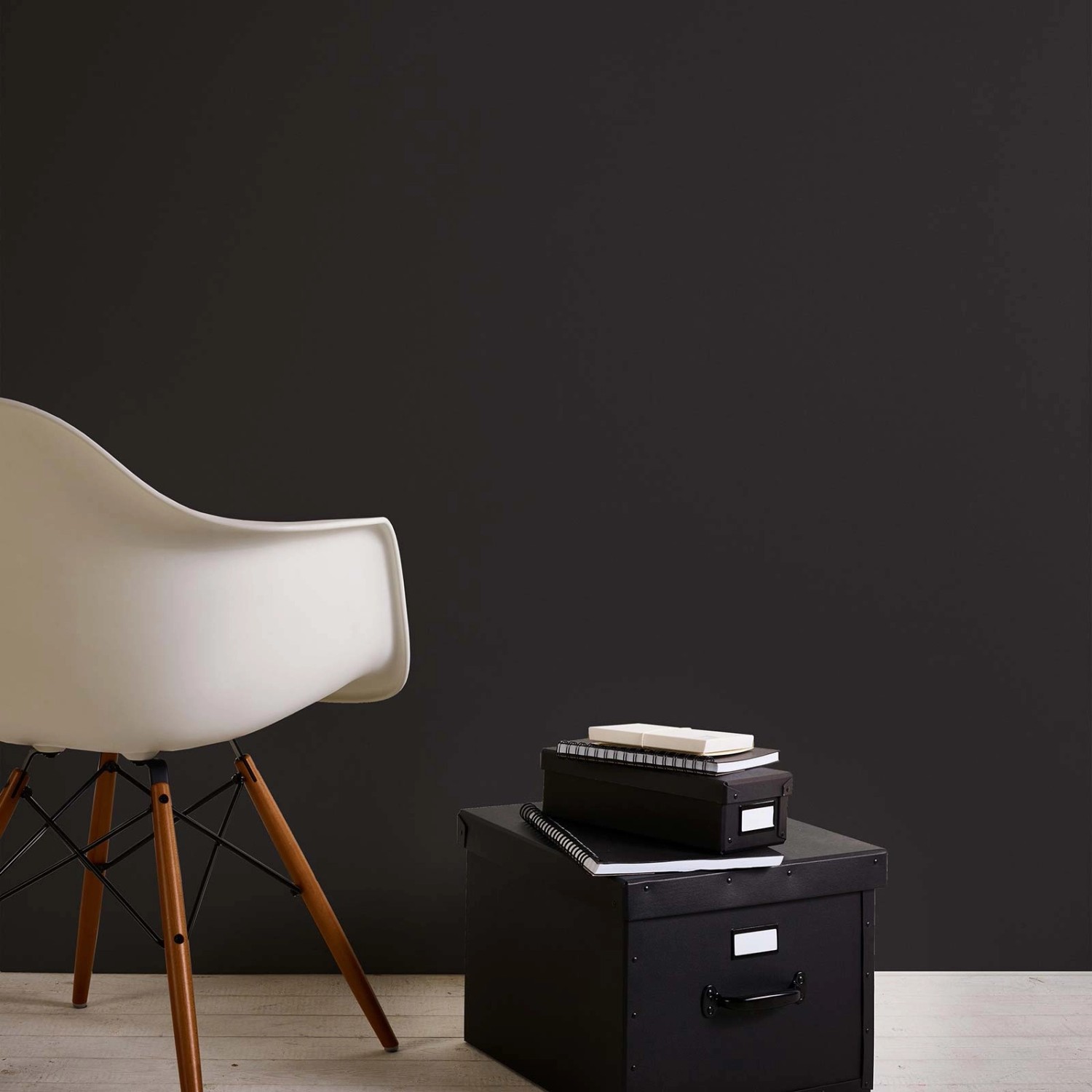Dunkle, einfarbige Bricoflor Tapete in Schwarz an der Wand, kombiniert mit weißem Stuhl und schwarzen Boxen.
