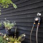 Fiskars Zeitschaltuhr mit 2 Ausgängen, montiert an einer Holzwand mit zwei angeschlossenen Schläuchen.