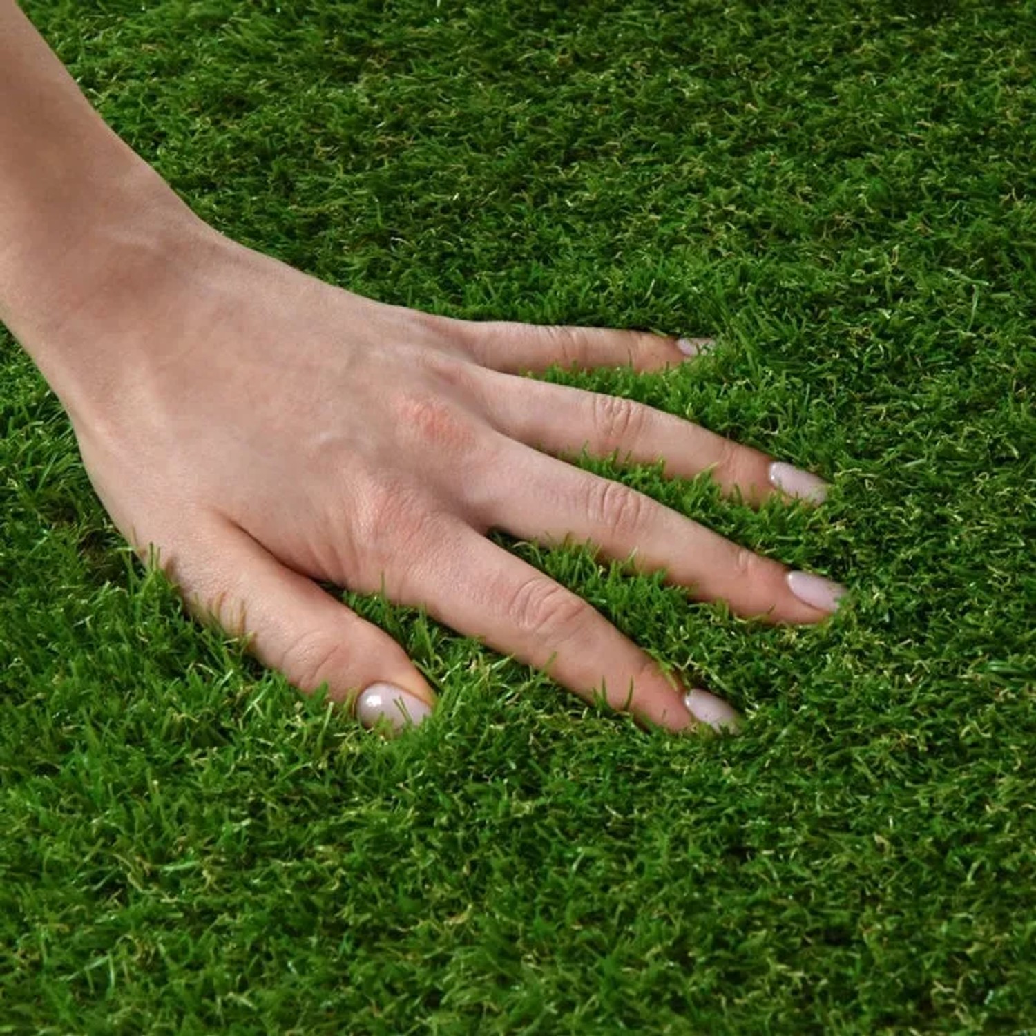 Nahaufnahme: Hand berührt weichen, grünen Karat Kunstrasen Tosca (35mm). Ideal für Balkon & Garten.