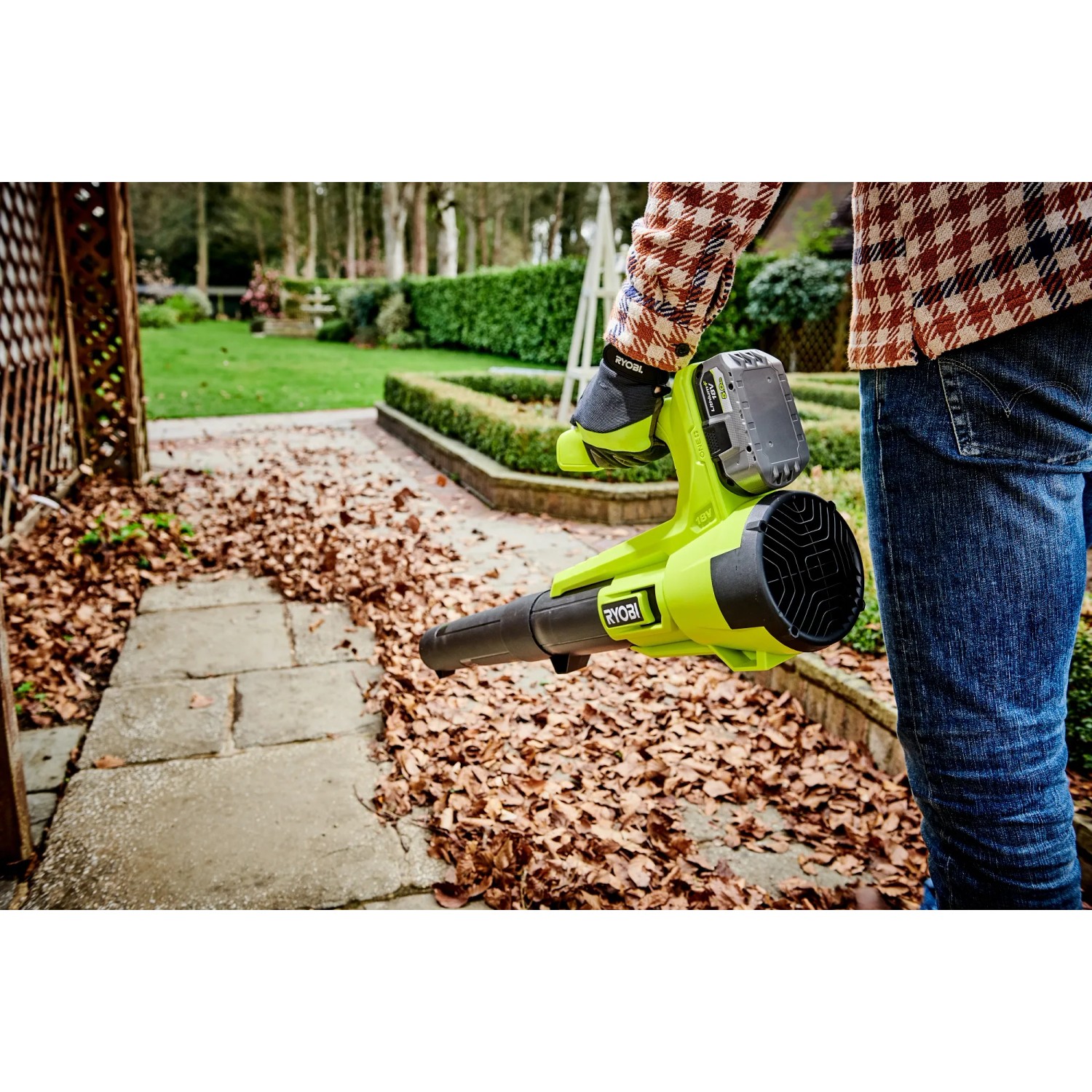 Ryobi Akku-Laubgebläse RY18BLA-140 One+ mit Akku und Ladegerät im Einsatz auf einer Terrasse.