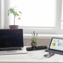 Schwarze 4-fach Steckdosenleiste mit USB-Anschlüssen, Laptop und Tablet auf einem Schreibtisch.