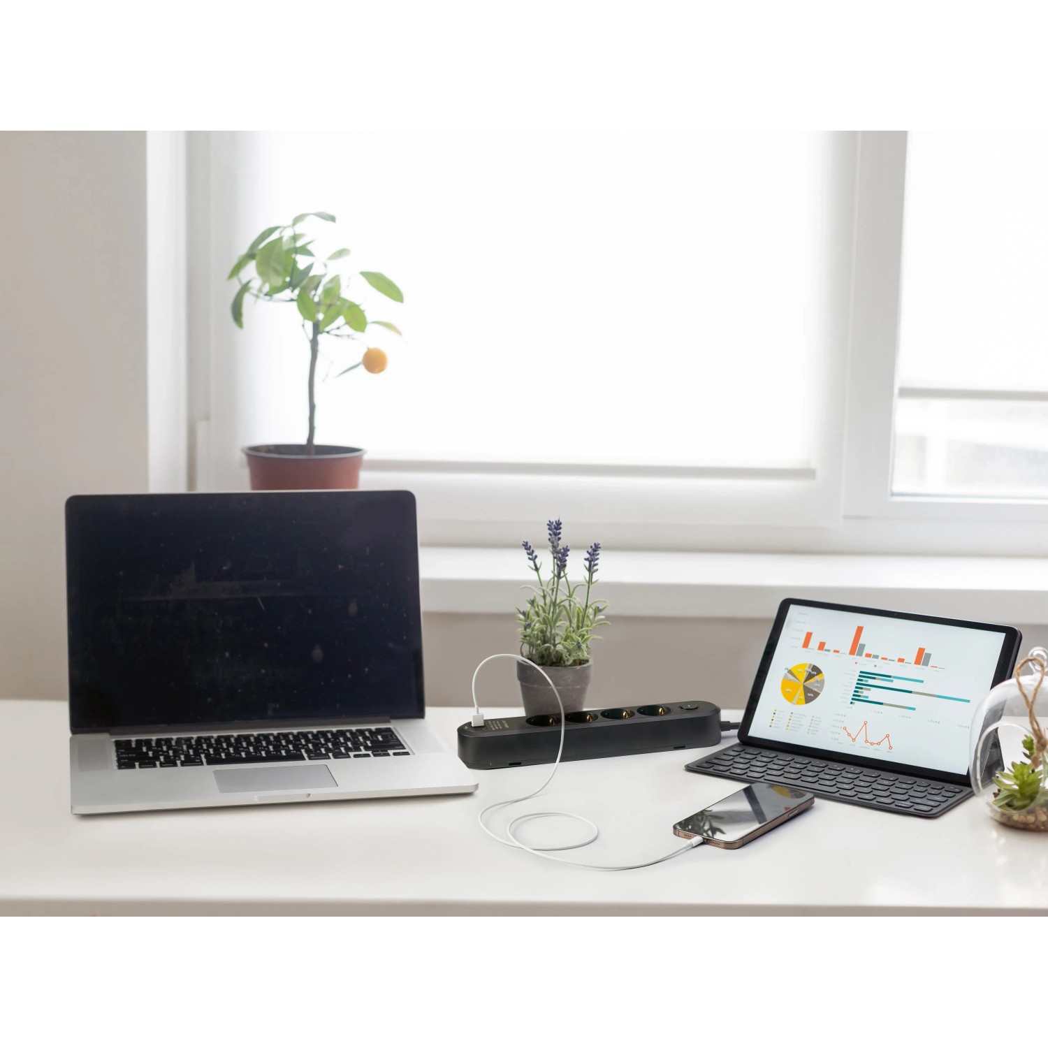 Schwarze 4-fach Steckdosenleiste mit USB-Anschlüssen, Laptop und Tablet auf einem Schreibtisch.
