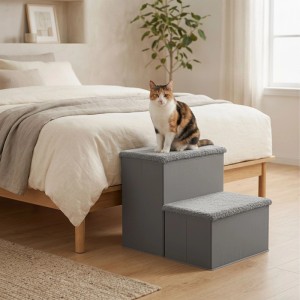 Graue 2-stufige Hundetreppe aus MDF/Polyester neben Bett. Eine Katze sitzt auf der oberen Stufe als Aufstiegshilfe.