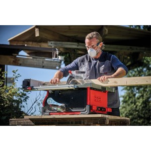 Mann mit Schutzbrille sägt Holz mit roter Einhell Tischkreissäge TP-CC 10 T im Freien. Präzise Zuschnitte von Brettern.