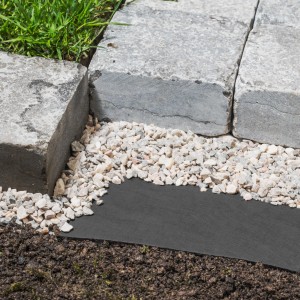 Graues Windhager Trennvlies 130 g/m² unter Steinen und Kies zur Unkrautbekämpfung.