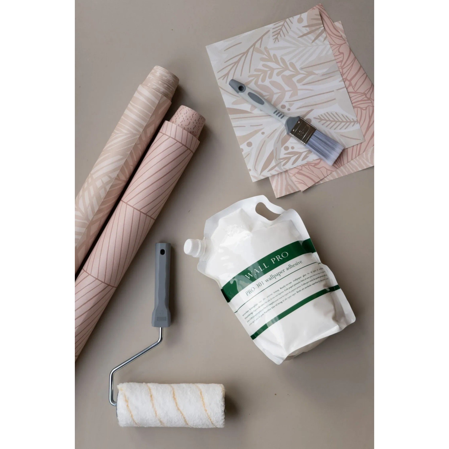 Wallpro Tapetenkleister mit Tapezierwerkzeug (Rolle, Bürste) und Tapetenrollen.