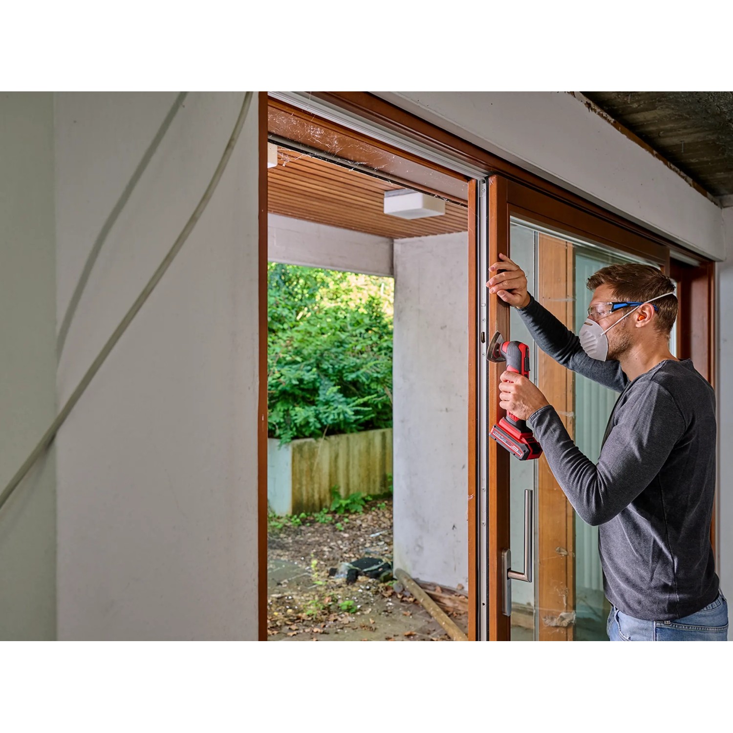 Mann arbeitet mit Einhell Multitool-Set XL an einem Fensterrahmen.