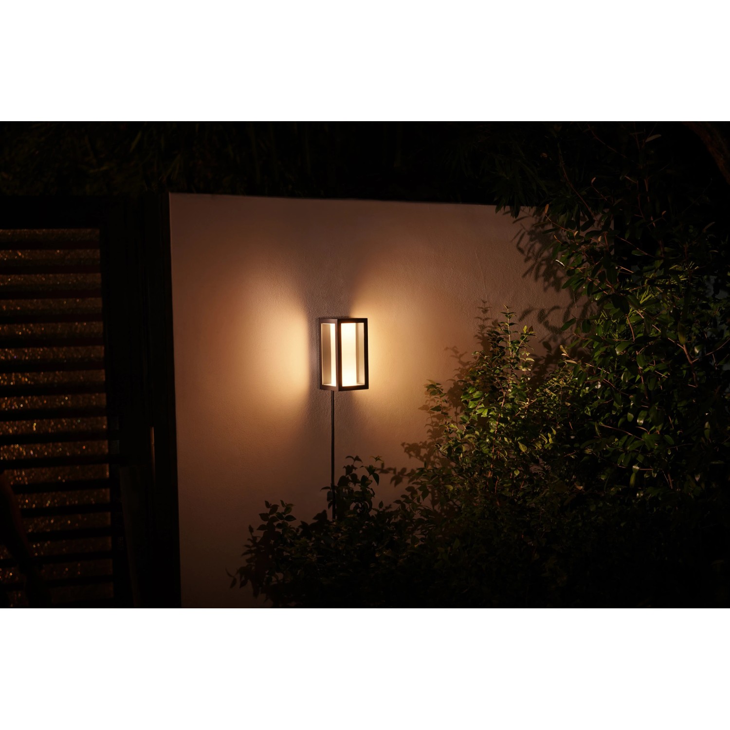 Philips Hue Impress Wandleuchte, schwarz, warmweißes Licht im Garten.
