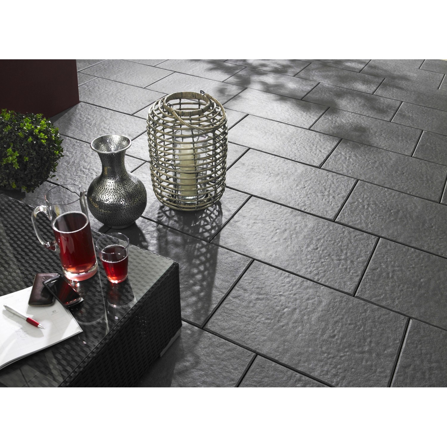 Verlegte Kann Terrassenplatte Sincera Anthrazit 60x40 cm auf Terrasse mit Tisch und Deko.