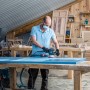 Handwerker schleift blaue Holzplatte mit Bosch Exzenterschleifer und Schleifblatt C470 K320.