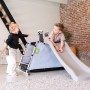 Exit Spielgerät My First Multiplay mit Rutsche und zwei Kindern beim Spielen im Haus.
