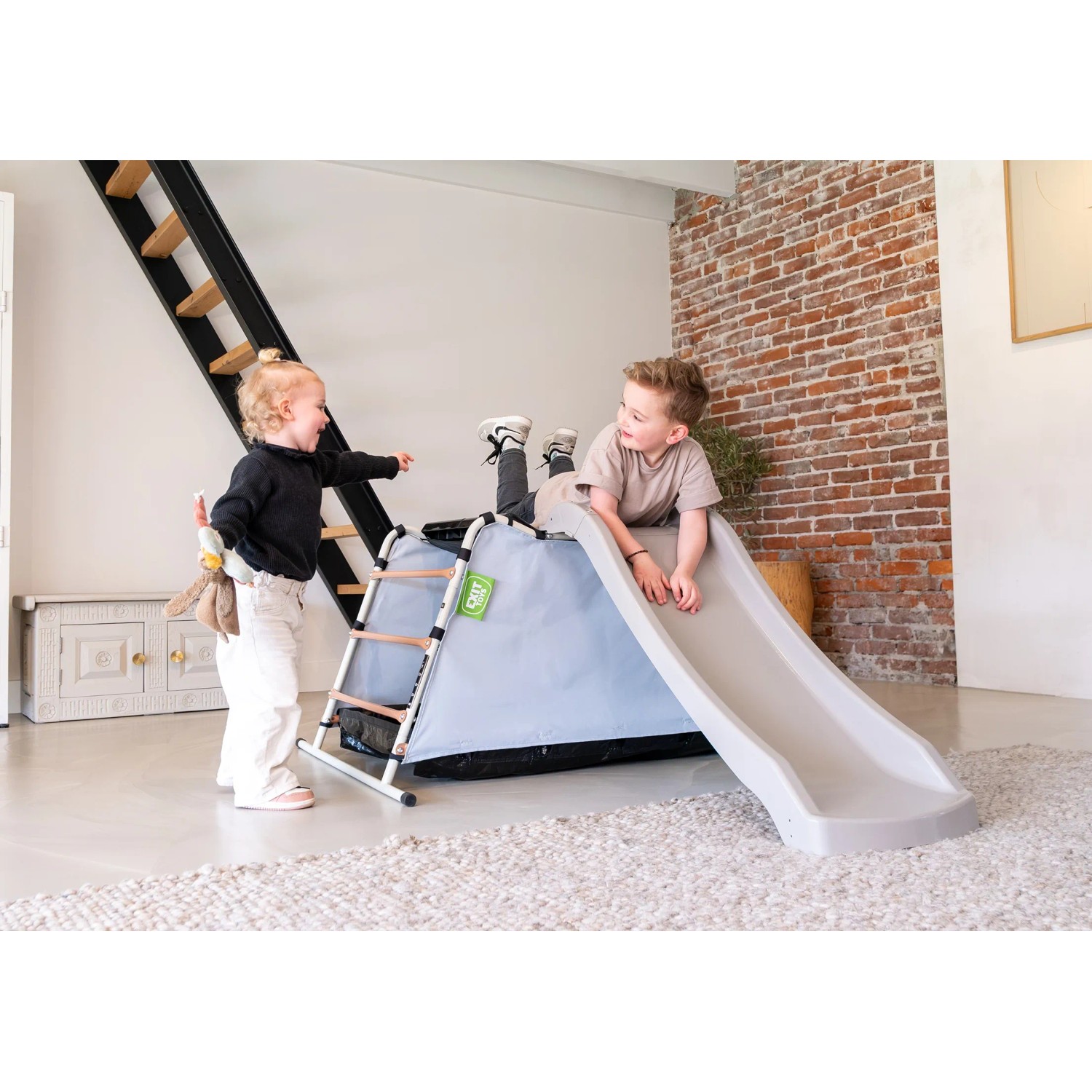 Exit Spielgerät My First Multiplay mit Rutsche und zwei Kindern beim Spielen im Haus.