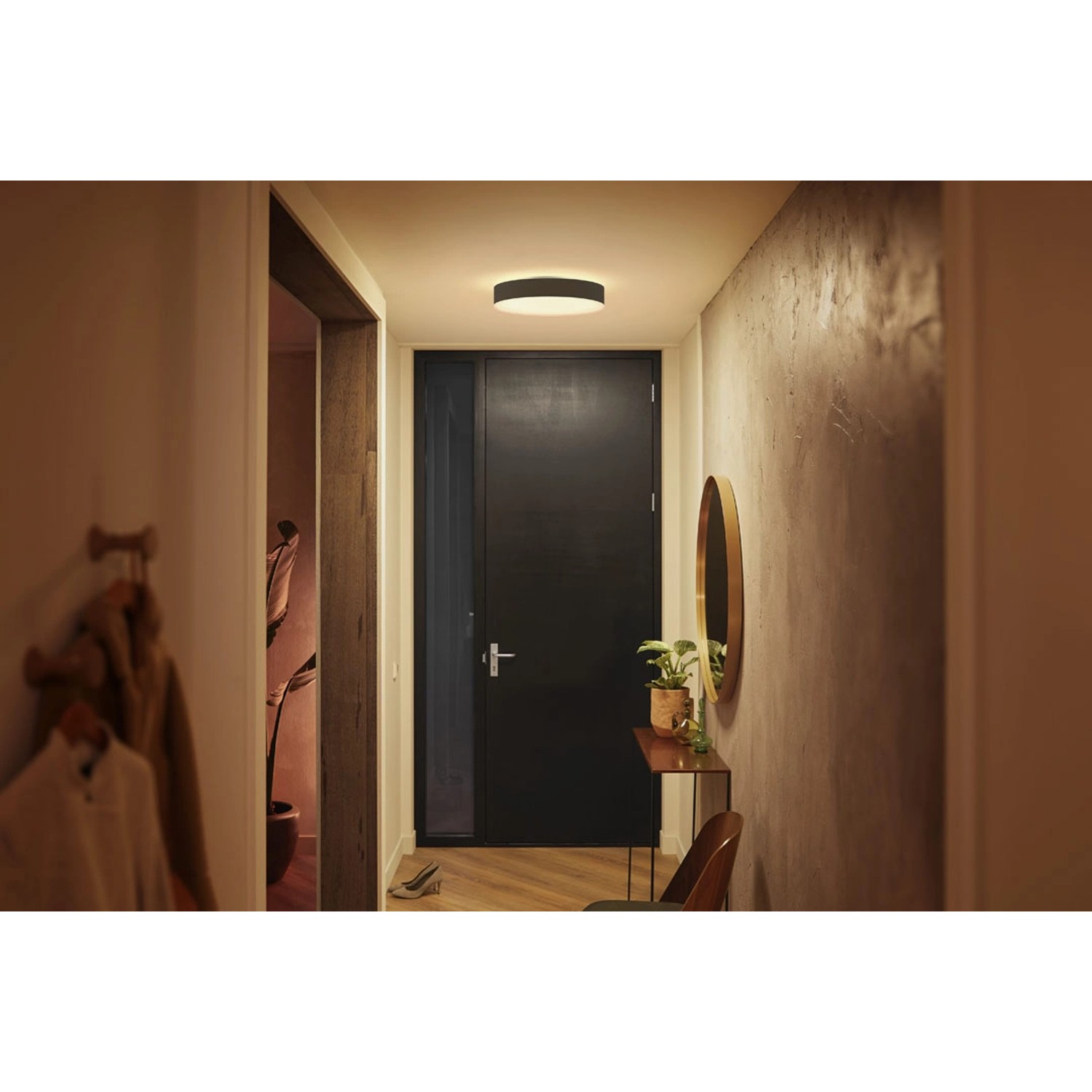 Schwarze Philips Hue Enrave M Deckenleuchte mit Dimmer, montiert an einer Decke in einem Flur.