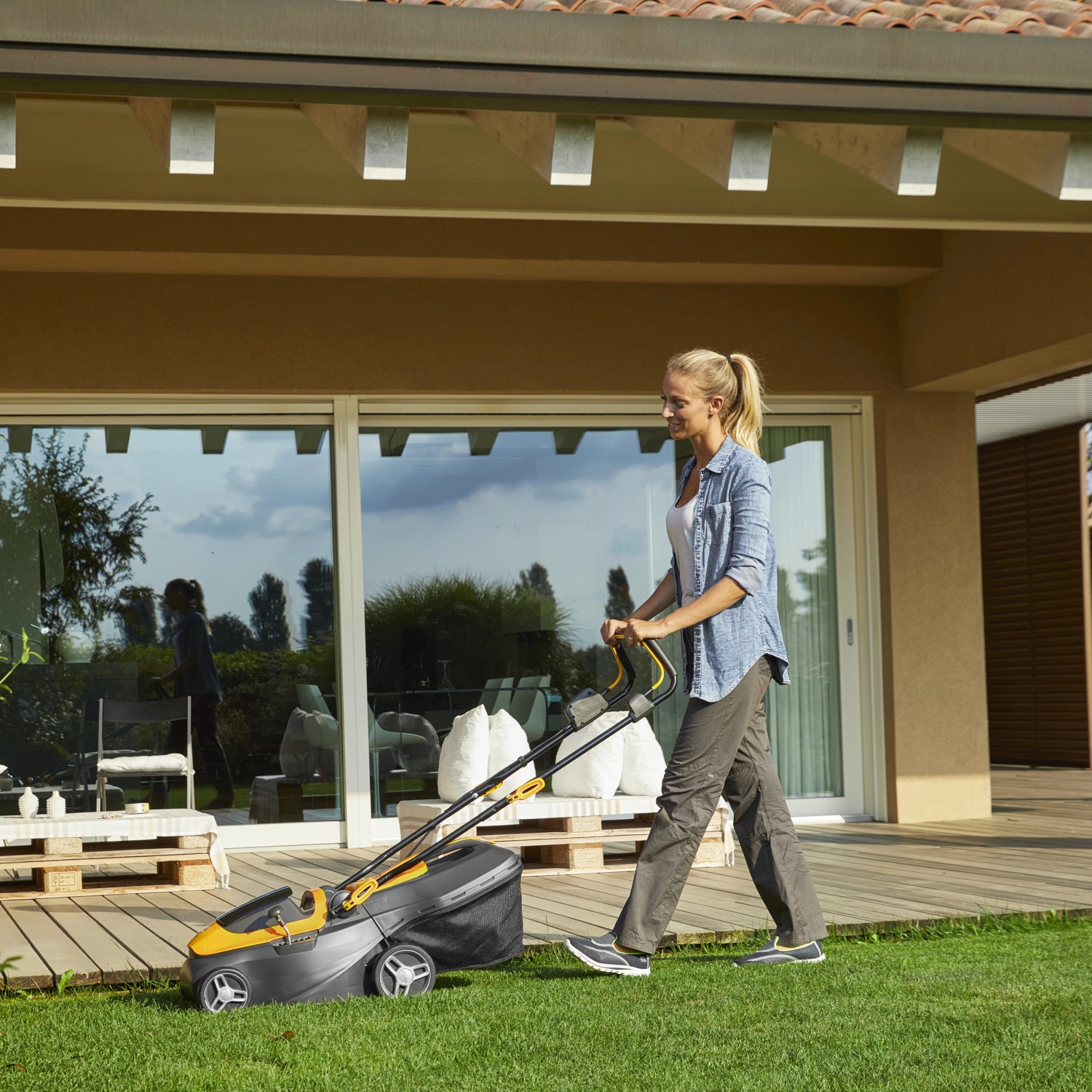 Frau mäht Rasen mit Stiga Akku-Rasenmäher Collector 136e mit Akku und Ladegerät.