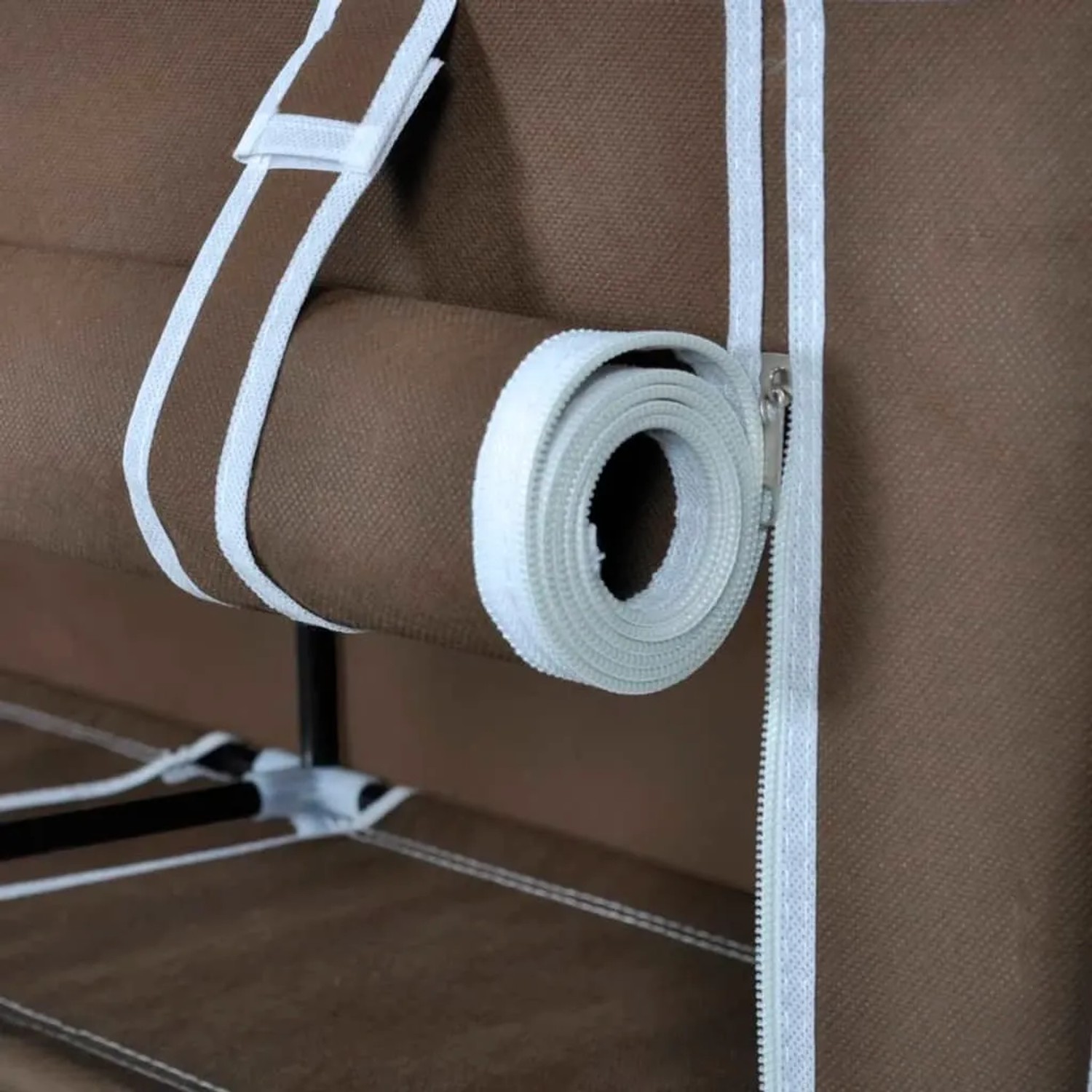 Detail des braunen Stoff-Schuhschranks: weißer Reißverschluss, aufgerolltes Halteband der Abdeckung.