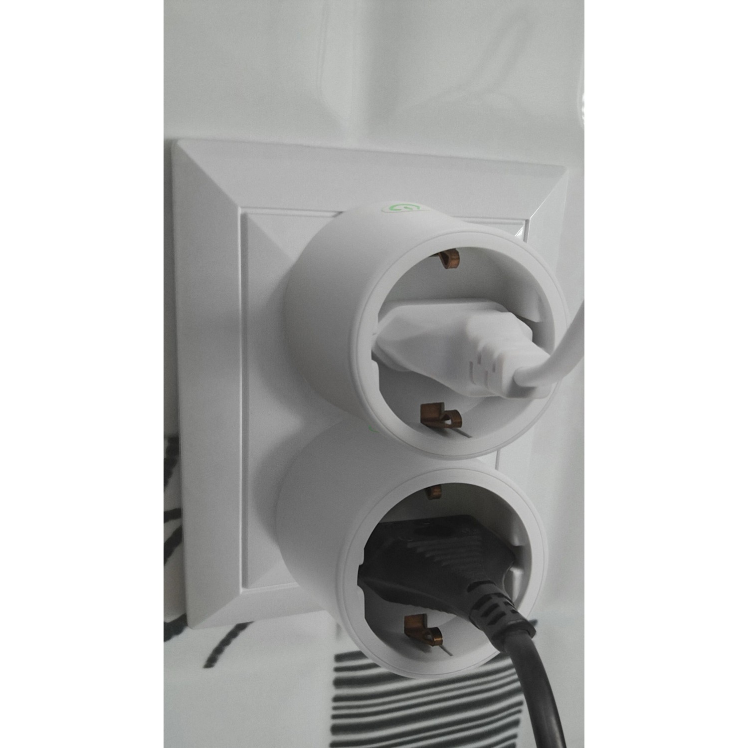 Osram Smart+ WiFi Matter Steckdose in Weiß, mit zwei eingesteckten Stromkabeln in einer Wandsteckdose.