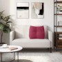 Weinrotes Samt-Rückenkissen auf hellem Sofa. Ergonomisches Kissen mit Knopf-Design für Komfort im Wohnzimmer.