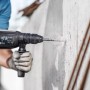 Bosch Flachmeißel SDS-max im Einsatz: Handwerker arbeitet mit dem Meißel an einer Betonwand.