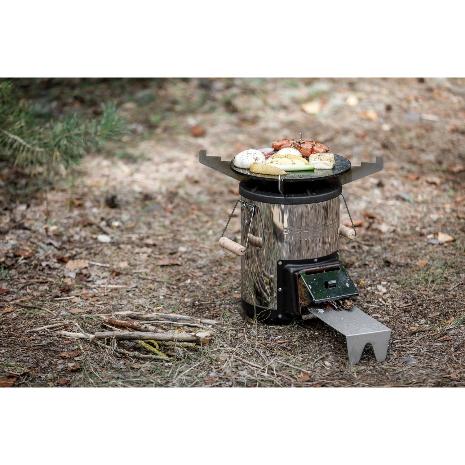 Petromax Raketenofen mit Grillplatte und Kochkreuz im Einsatz mit Grillgut.