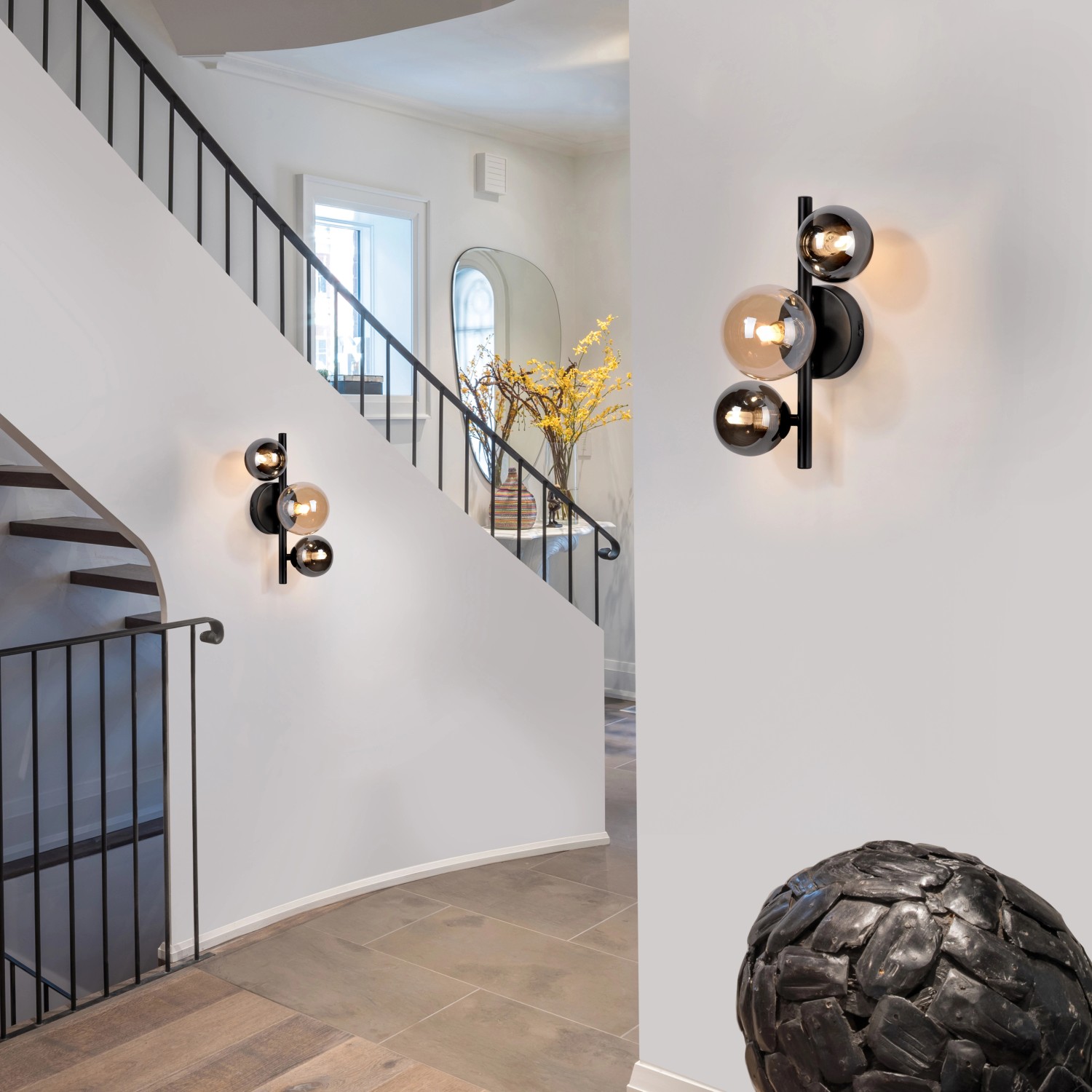 Schwarze Paul Neuhaus Wandleuchte Popsicle mit 3 Glaskugeln (Amber, Rauchglas) im Treppenhaus.