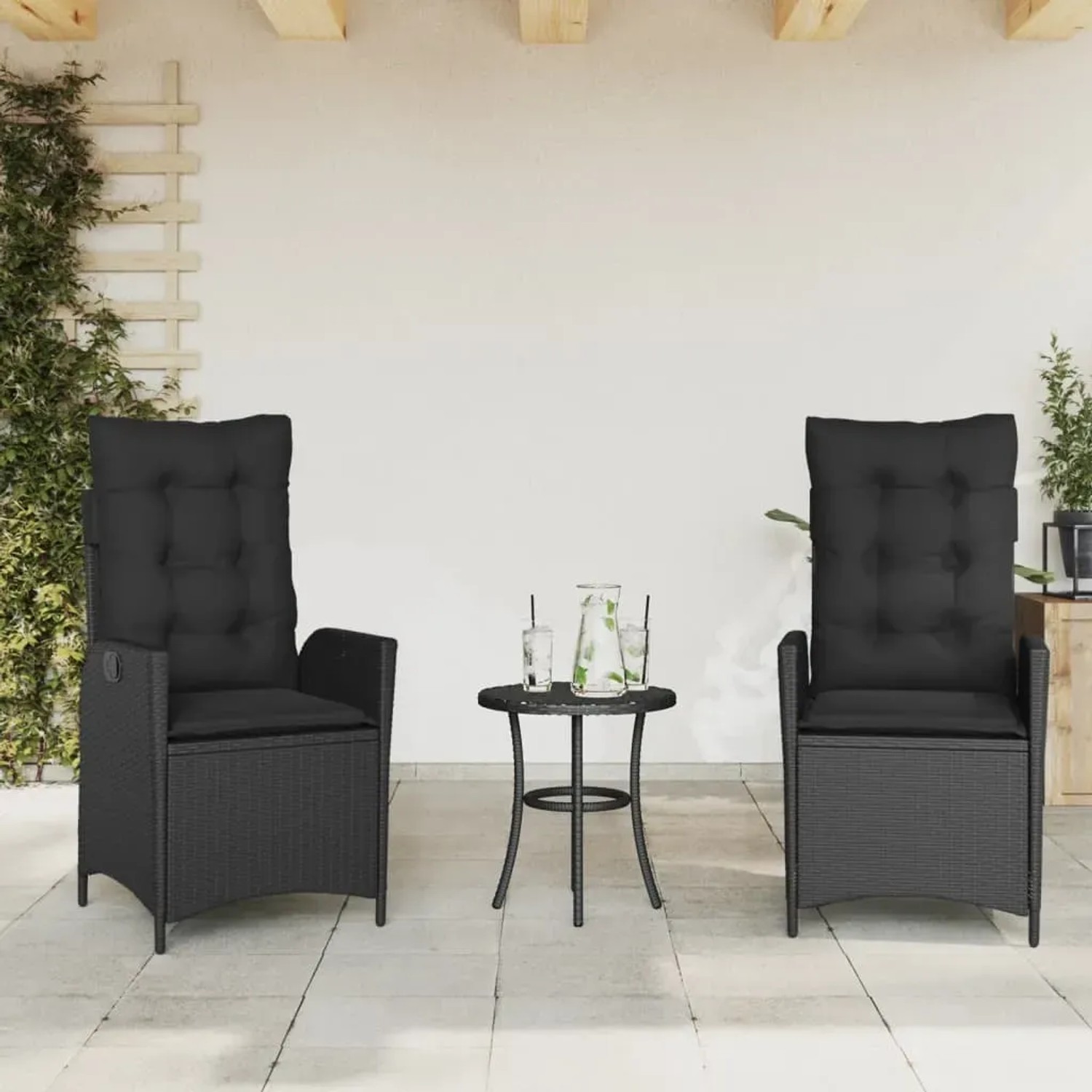 2 schwarze, verstellbare Gartensessel aus Poly Rattan mit Kissen, neben einem kleinen Tisch.