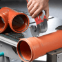 Einhell Multitool im Einsatz: Schneiden eines orangefarbenen Kunststoffrohrs. Zubehör für Multifunktionswerkzeuge.